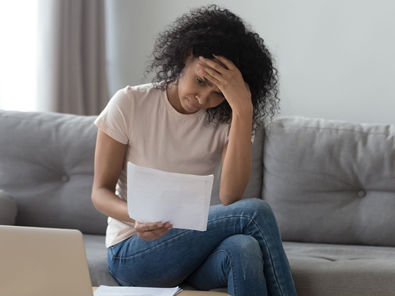 Stressed african woman holding bills worried about bankruptcy bank debt